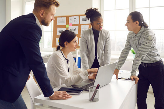 Group of mixed race business people working on project, discussing ideas and making suggestions. Digital marketing team using laptop computer and discussing customer focused content in office meeting