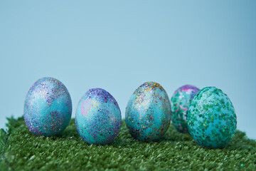 Blue painted eggs with bright shiny gliter on grass