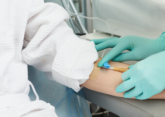 Beautician inserts a needle into a patient's vein in order to draw blood for cosmetic procedures...