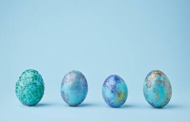 Blue painted eggs with bright shiny gliter on blue background