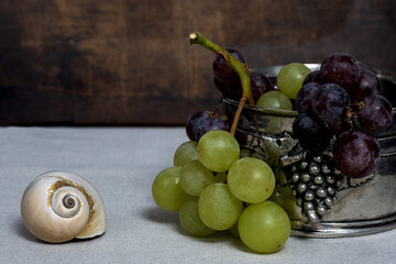 Still life with white and blue grapes in a pewter bowl