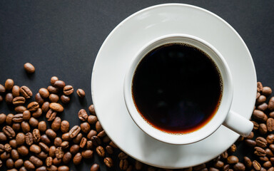 Fototapeta na wymiar Cup of black coffee on black background with roasted coffee beans