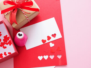 White and red paper, heart-shaped punches, red bow tie gift box  and decorations for making a love card on a pink background. Space for your text...