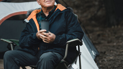 Chill senior man having coffee next to his tent