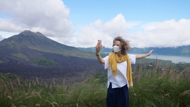 Caucasian Woman Wearing Face Mask Having Video Call In The Mountains, Showing The Landscape. Staying Connected During Corona Virus