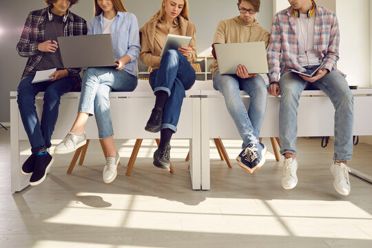 Cropped image of students sitting on the desks with modern gadgets and preparing for lectures. Concept of learning, work, digital technology and modern gadgets for the learning process.
