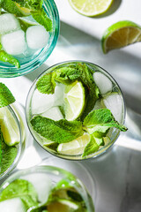 Mojito cocktail with mint and lime in glasses, white marble background, top view, close up.. Refreshing drink with lime and mint in glasses.