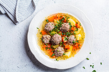 Homemade meatballs soup with vegetables in white plate, gray background, top view, copy space. - obrazy, fototapety, plakaty