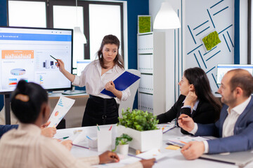 Business executive delivering a presentation to his colleagues during meeting. Corporate staff discussing new business application with colleagues looking at screen.