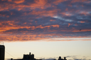 early morning winter sunrise with silhouettes of rooftops against a blue-red and orange sky