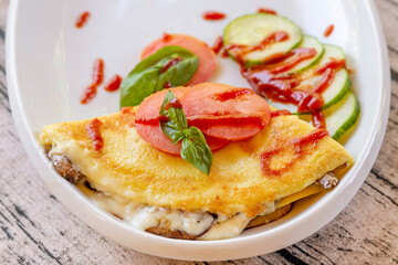 A tasty savory crepe with aubergines, courgettes and tomatoes on a white plate, with basil leaves decoration