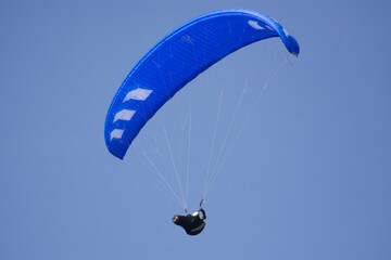 red paraglider on the blue sky in different colours