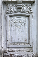 classic ornaments carved from white painted wood on a weathered and chipped old door - blank framed surface with texture
