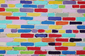 A fragment of a textured creatively decorated brick wall with bricks of different colors