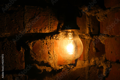 Old Light Bulb Dimly Illuminating The Brick Wall Of A Dark Scary Room  Mysterious Symbol For A Wallpaper Antique Wall Mural | Antiq-Domingo