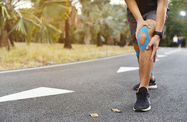 close up of young Asian sports man has pain at muscles and joints during outdoor exercise, over trainning or running and sport injuty concept