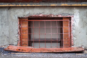 Fototapeta na wymiar An old window covered with iron bars minus the first floor of a residential building of the sixties of the twentieth century