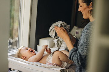 Mother getting her baby dressed - Powered by Adobe