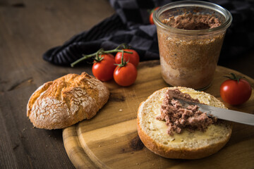 Grobe Leberwurst im Glas aus Vorrat mit Brötchen, Butter und Tomaten als Vesper Brotzeit auf...