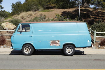 Fototapeta na wymiar Old Faded Blue van parked on street with rust spot