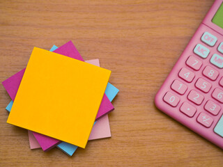 The notepad is placed on the wooden floor and the calculator is placed on the right.