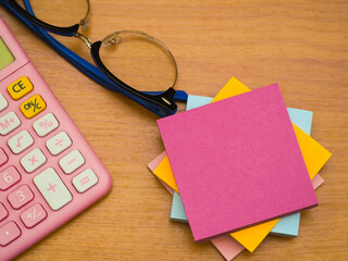 Notepads are placed on top of each other and a calculator is placed on the left side with glasses.