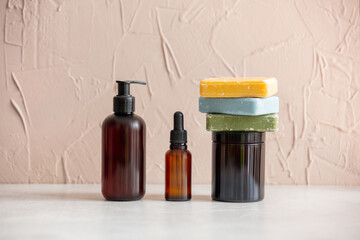 Two dark bottles and one jar with soap on yellow background