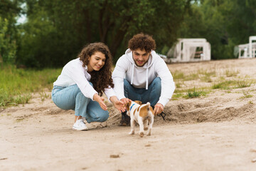 Guy with girl playing with doggy on beach