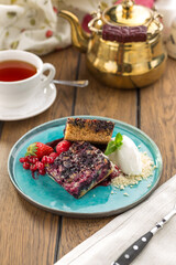 Blueberry crumble with ice cream and cup of tea on wooden table