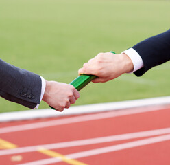 Businessmen pass on the baton in relay race in stadium