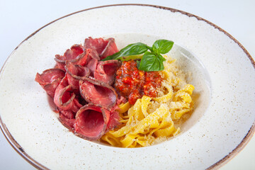fresh pasta with cheese and meat sauce on a white plate in the studio