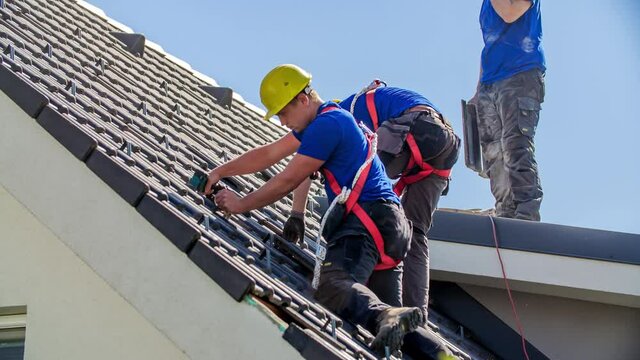 Roof workers mending roof tiles on sunny day