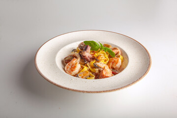fresh pasta with seafood on a white plate in the studio