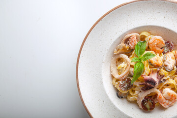 fresh pasta with seafood on a white plate in the studio