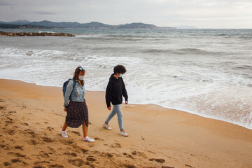 une femme et un garçon sur la plage. Des touristes masqués marchant sur la plage. Une mère et son fils en vacances à la mer.