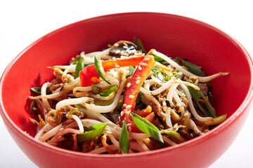 Udon noodle with teriyaki chicken and vegetable. Asian style noodle food on white background. Teriyaki chicken noodle in red bowl with sesame and onion.