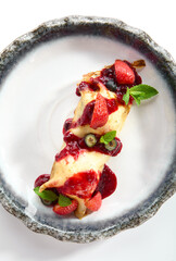 French Style Crepes - Cream Crepes with Berry and Fruit. Pancake Breakfast on white and blue plate isolated on white background. Mixed berry crepes garnished with mint and sweet sauce top view.