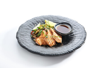 Teppanyaki Style Salmon - Grilled Salmon Fillet with Soy Sauce and Vegetables. Japanese Teppanyaki Salmon Steak garnished with lemon and green beans leaf. Black asian plate on white background.