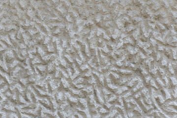 A solid wall of rough gray cement with irregular indentations