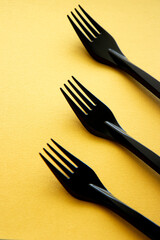 Black bamboo forks on bright yellow background. Abstract background with eco cutlery