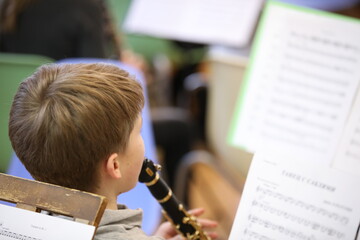 Child boy plays a musical instrument clarinet.Close-up of the head of a schoolboy with sheet music...