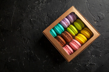colored fresh macarons in the studio on a black background in a box