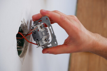A man repairs a lighting switch. Close-up on hand. Electrician work.