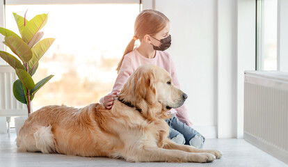 Little girl in mask with golden retriever dog
