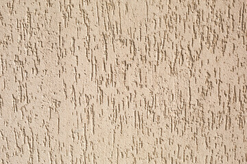 Plaster on the wall with a bark beetle pattern of beige and sand color. Background, texture. Exterior decoration of building, house.