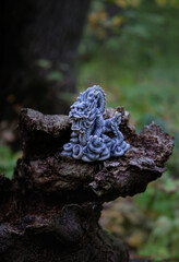 asian dragon statue on old tree trunk, natural forest background. beautiful stone dragon, symbol of wisdom, good start, Imperial power, deity. Fabulous atmosphere mystery witchcraft composition