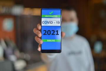 Covid-19 Health Passport. Vaccinated man holding cell phone with covid 19 vaccination proof
