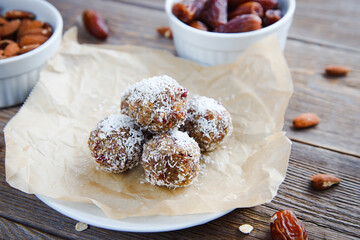 Balls or candies of dried fruits, nuts and oatmeal, sprinkled with coconut on a wooden background. Energy balls. Healthy food, snack