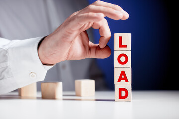 The word load written on tiered wooden cubes with a businessman hand is about to flip the cubes.