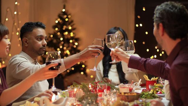 winter holidays, celebration and people concept - happy friends having christmas dinner at home and drinking non-alcoholic wine